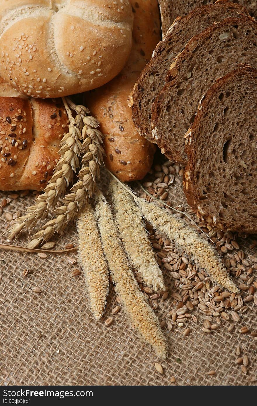 A close up of a different bread with wheat grains and stalks placed next to it.
. A close up of a different bread with wheat grains and stalks placed next to it.