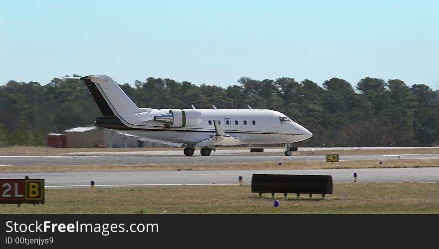 A large white private jet on final before takeoff on a runway. A large white private jet on final before takeoff on a runway