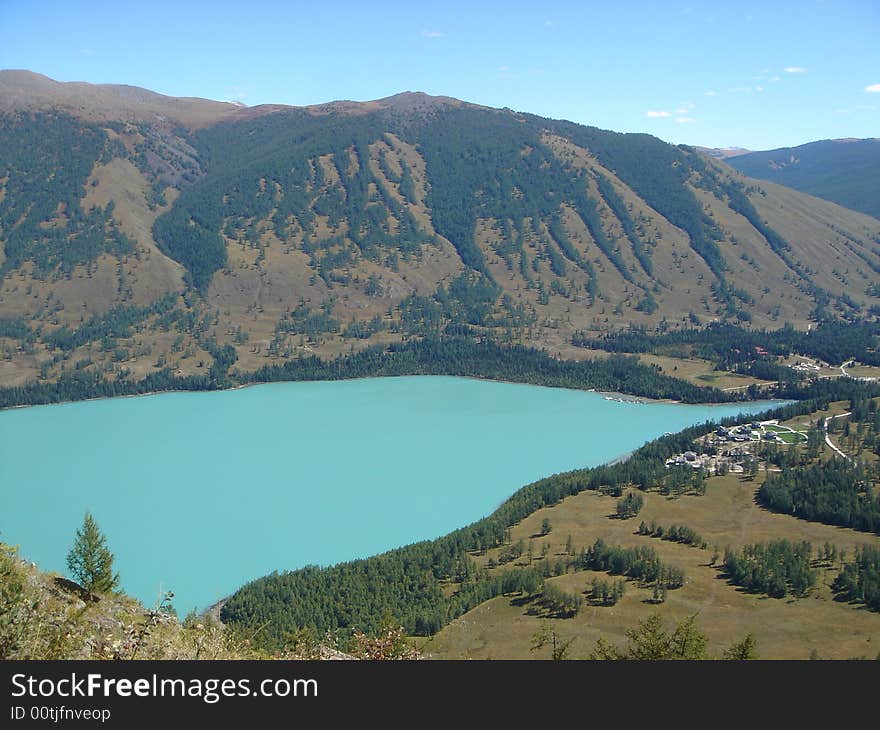 A beautiful blue river going through a vast green plain surrounded by mountain ranges in xing-jiang province, china. A beautiful blue river going through a vast green plain surrounded by mountain ranges in xing-jiang province, china