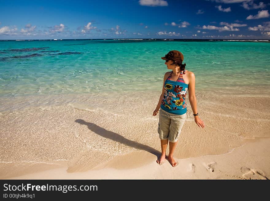 Young woman standing on tropical white sand beach by turquoise waters. Young woman standing on tropical white sand beach by turquoise waters