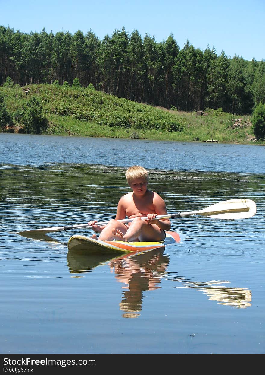 Boy is paddling on a calm lake. Boy is paddling on a calm lake