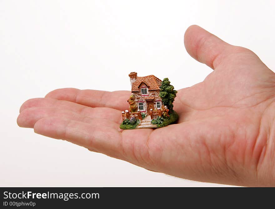 A small porcelain figurine of a country house on the human hand. A small porcelain figurine of a country house on the human hand.