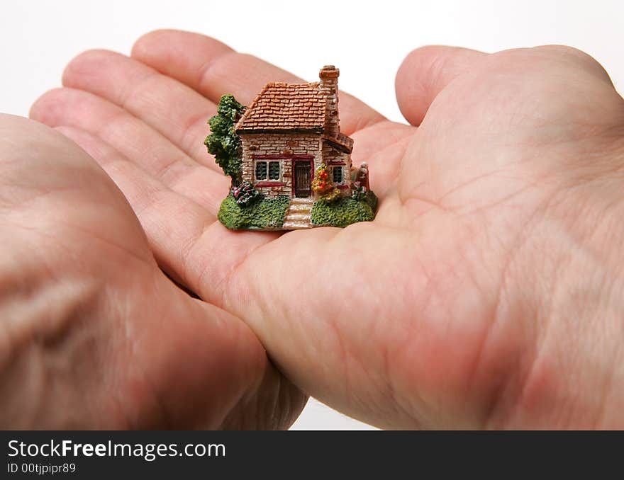 A small porcelain figurine of a country house supported by hands. A small porcelain figurine of a country house supported by hands.