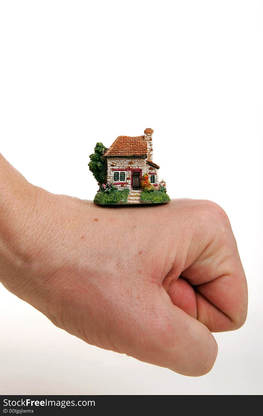 A small porcelain figurine of a country house supported by fist. A small porcelain figurine of a country house supported by fist.