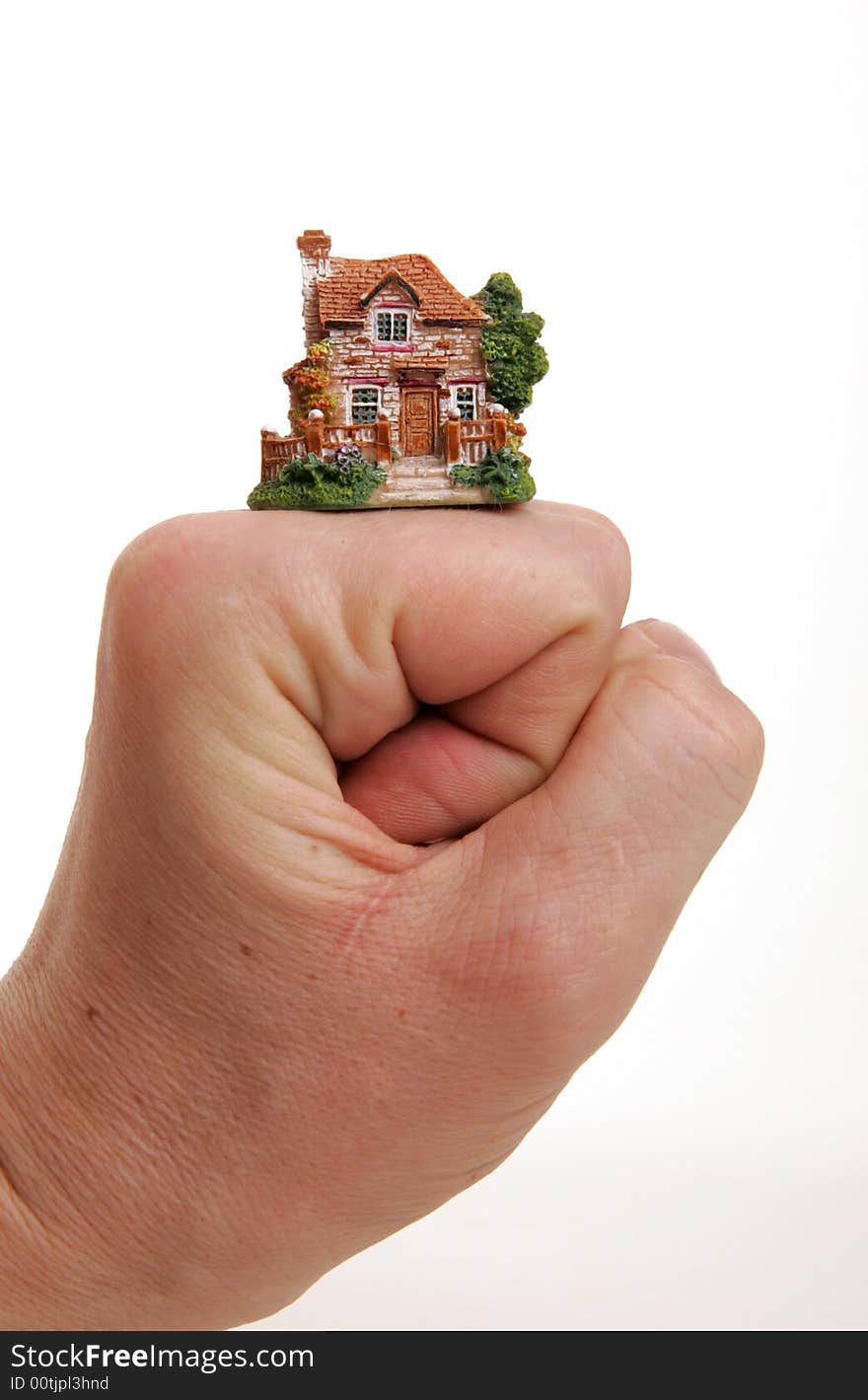 A small porcelain figurine of a country house supported by the fist.