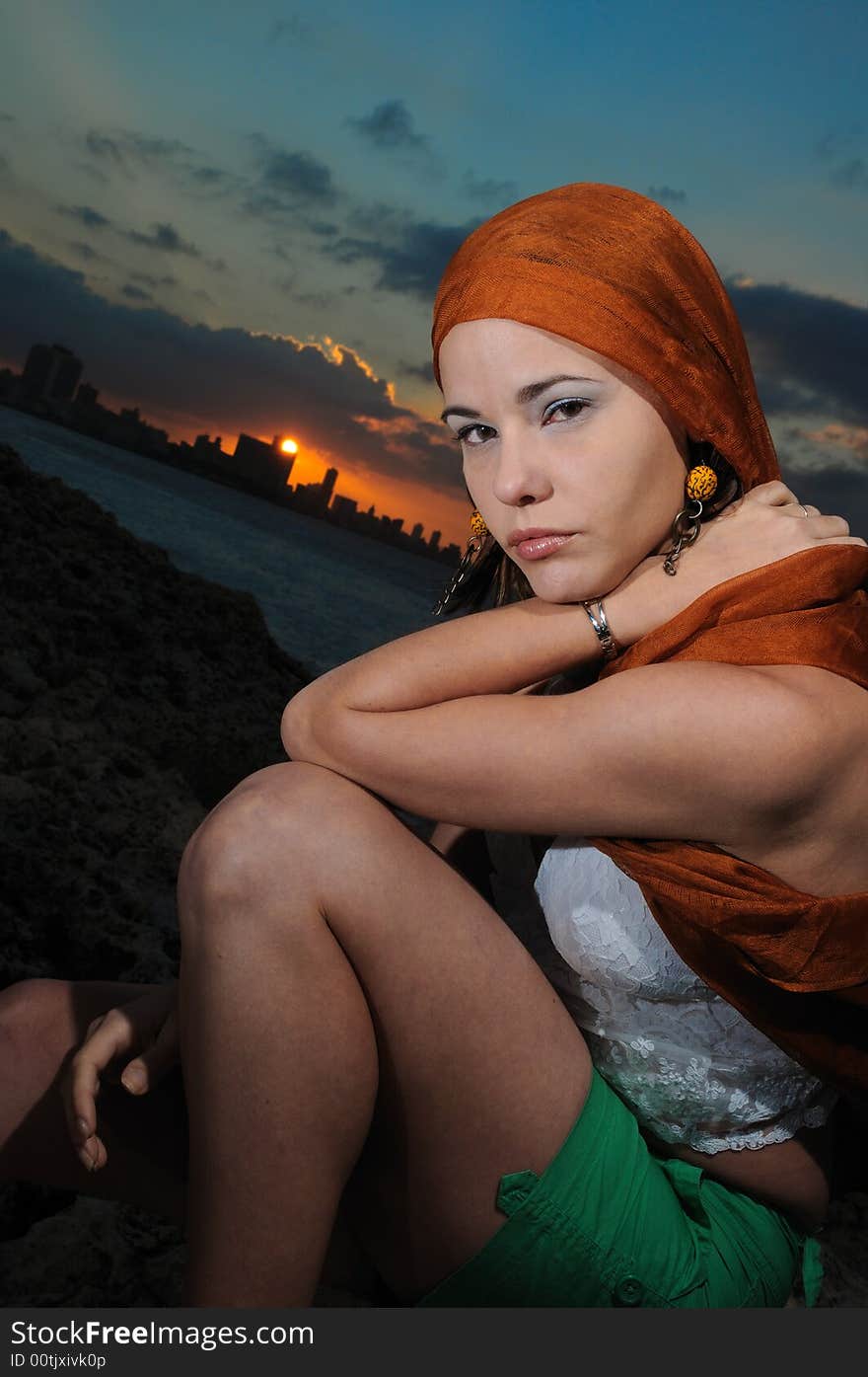 Fashion model sitting outdoors at sunset - havana skyline on the background. Fashion model sitting outdoors at sunset - havana skyline on the background