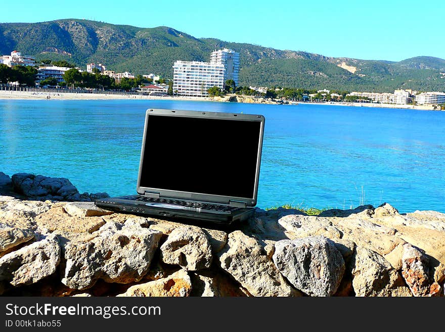 Laptop with beach view behind and blank screen for text. Laptop with beach view behind and blank screen for text