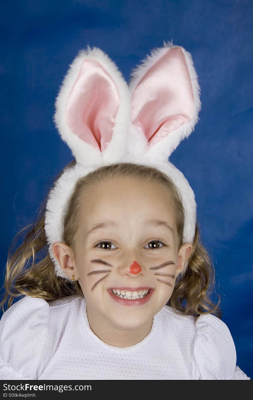 Little girl smilling with bunny ears over blue background. Little girl smilling with bunny ears over blue background