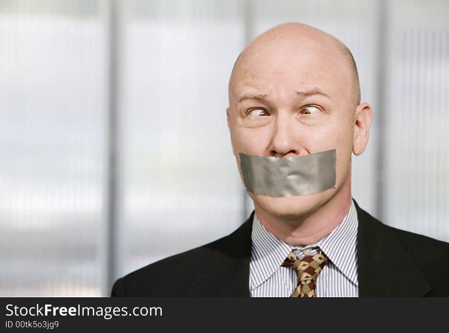 Cross-eyed businessman silenced with duct tape over his mouth. Cross-eyed businessman silenced with duct tape over his mouth