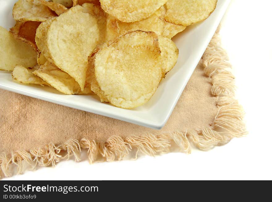 Potato chips close up on a square white dish. Potato chips close up on a square white dish.