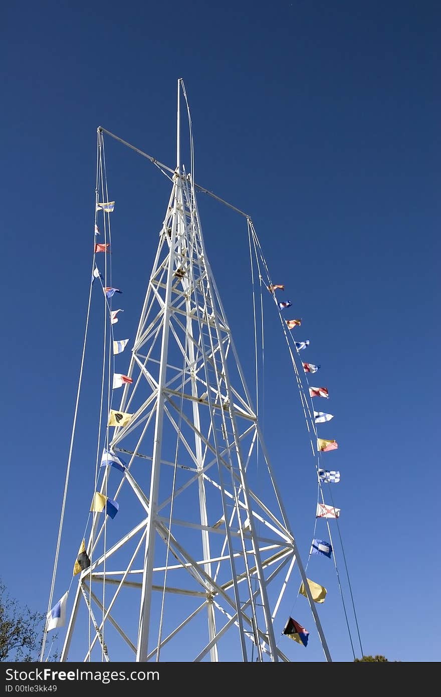 A white tower against a blue sky with nautical flags blowing in the breeze. A white tower against a blue sky with nautical flags blowing in the breeze