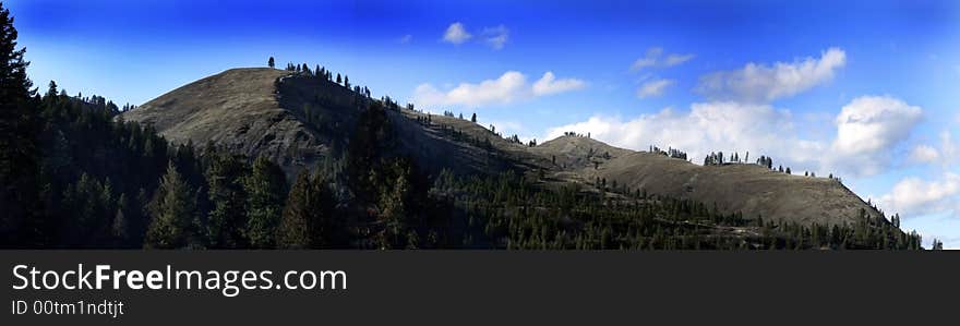 Panoramic of mountains with trees in the foreground and clouds in the background. Panoramic of mountains with trees in the foreground and clouds in the background.