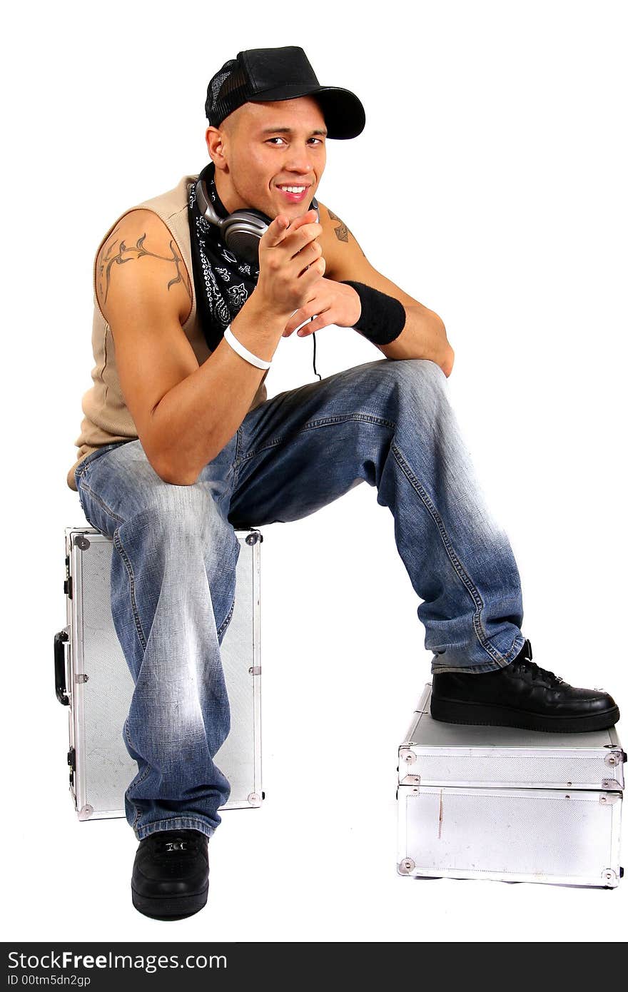 Young man sitting on dj cases with headphones and lots of tattoos. Young man sitting on dj cases with headphones and lots of tattoos.