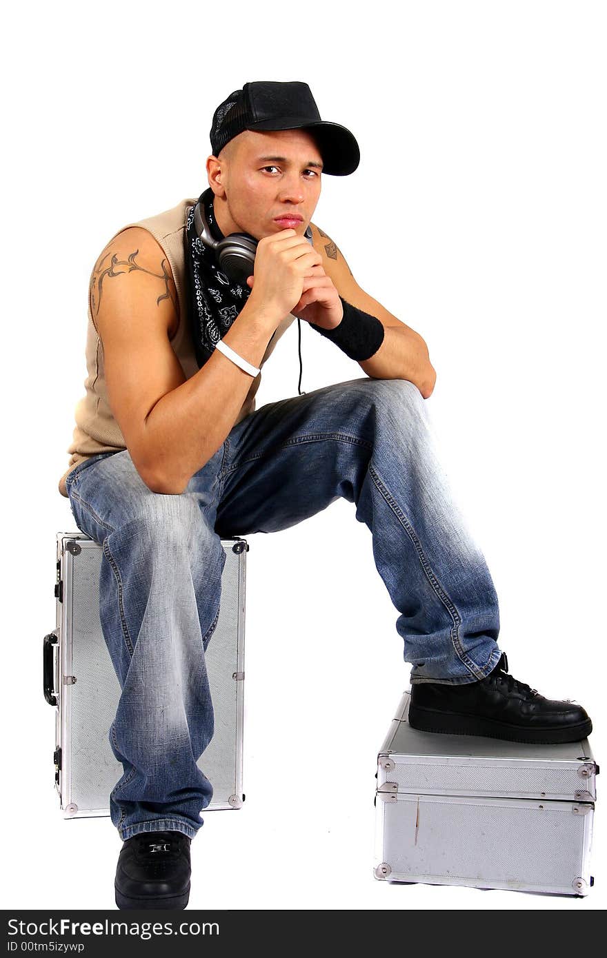 Young man sitting on dj cases with headphones and lots of tattoos. Young man sitting on dj cases with headphones and lots of tattoos.