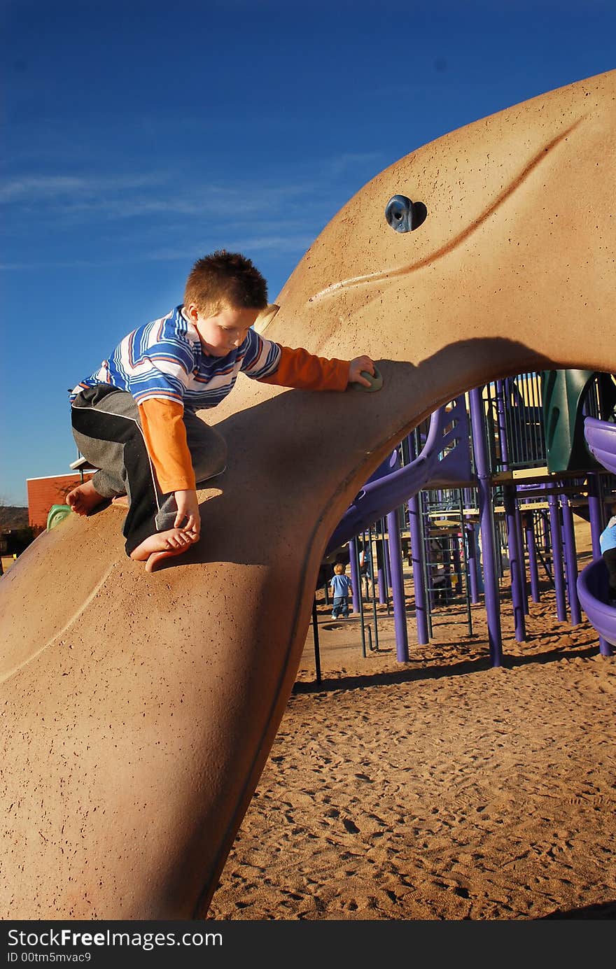 Barefoot boy climbs rock wall at playground. Barefoot boy climbs rock wall at playground.