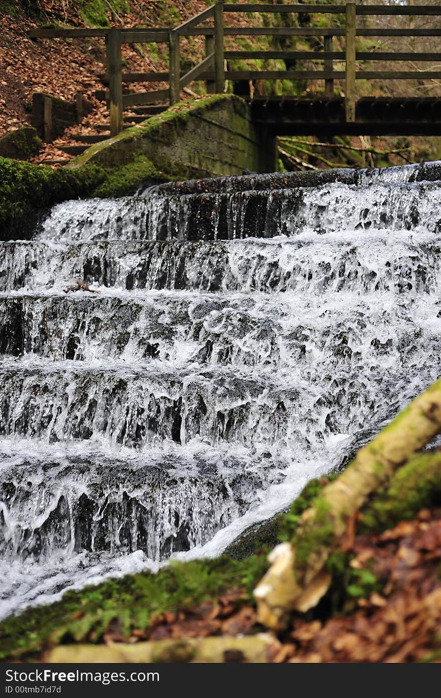 Man Made water fall with bridge crossing in woodland. Man Made water fall with bridge crossing in woodland.