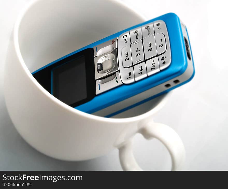 A mobile phone in a white cup