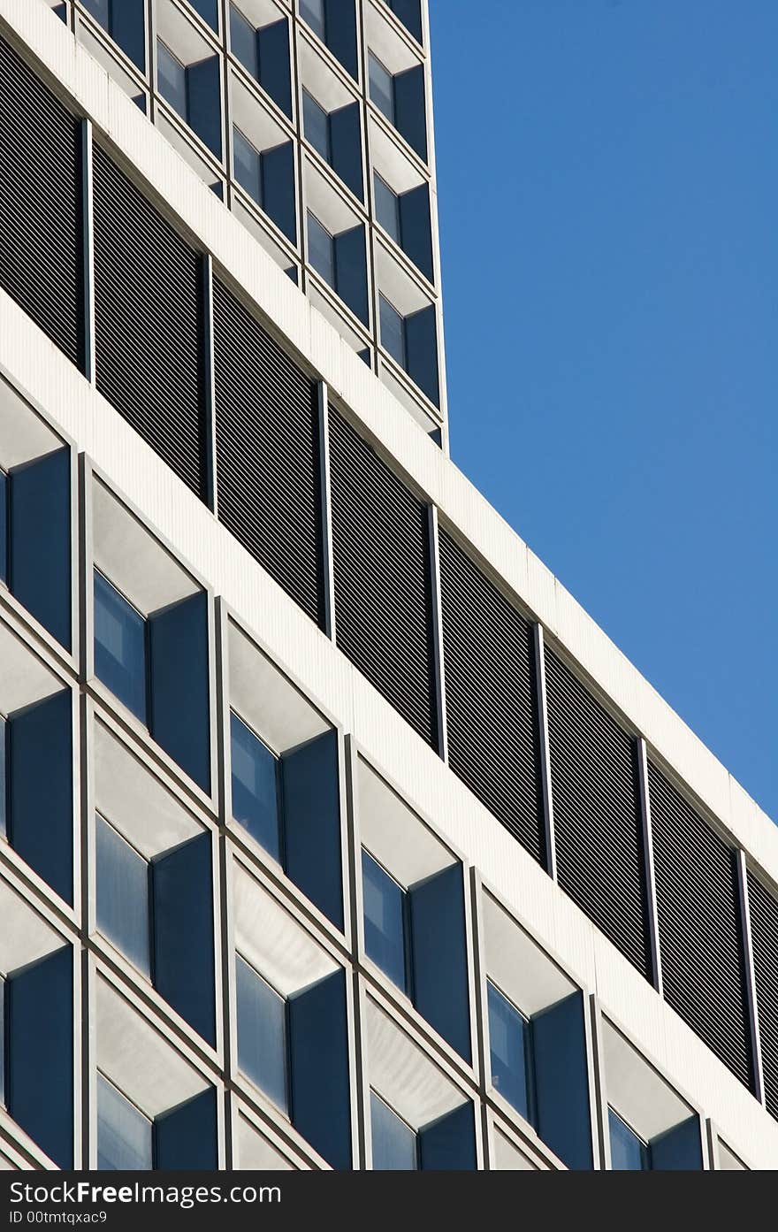 Architectural detail of a modern high-rise building with blue sky serving as the background. Architectural detail of a modern high-rise building with blue sky serving as the background.