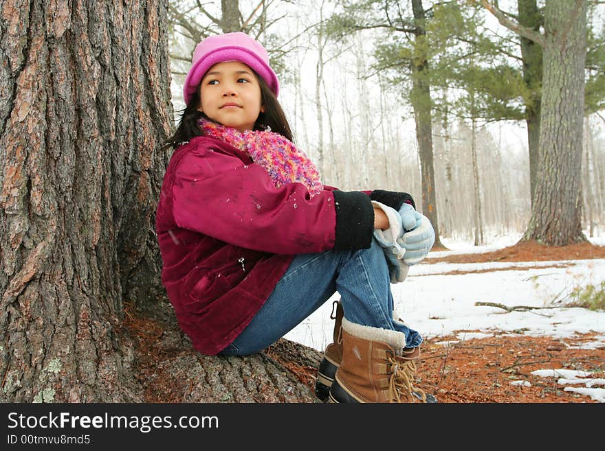 Nine year old girl enjoying sitting under tree in winter. Nine year old girl enjoying sitting under tree in winter