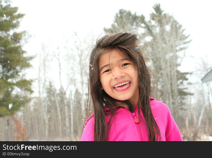 Child sticking out tongue while playing outdoors in winter