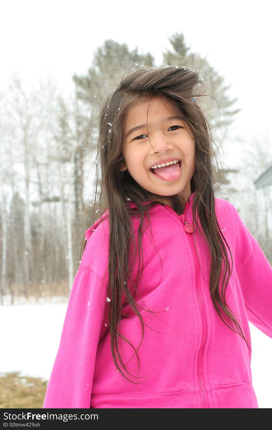 Child sticking out tongue while playing outdoors in winter