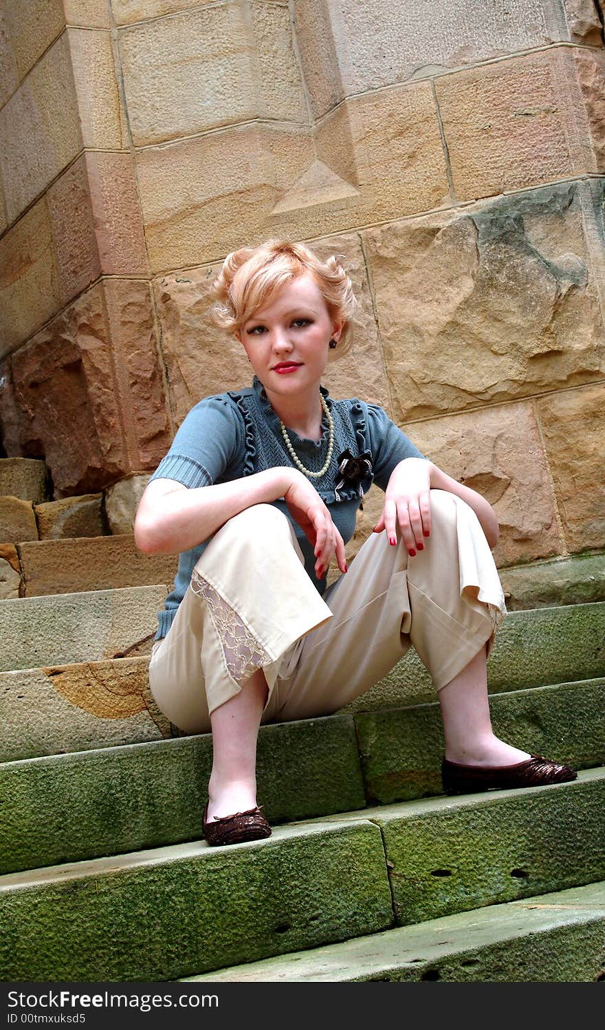 Young blond woman sitting on stone steps. Young blond woman sitting on stone steps