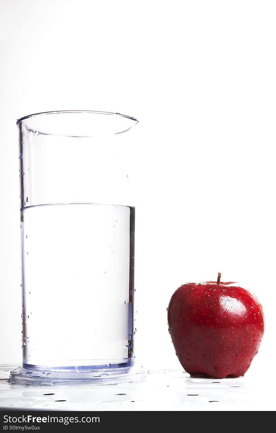 A glass of water next to a red delicious apple. A glass of water next to a red delicious apple