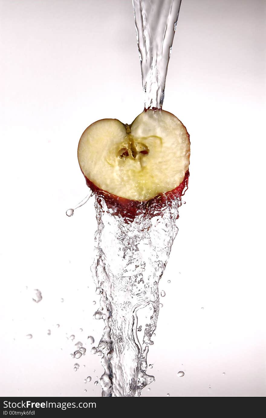 Water pouring  and splashing over a red delicious apple on white. Water pouring  and splashing over a red delicious apple on white