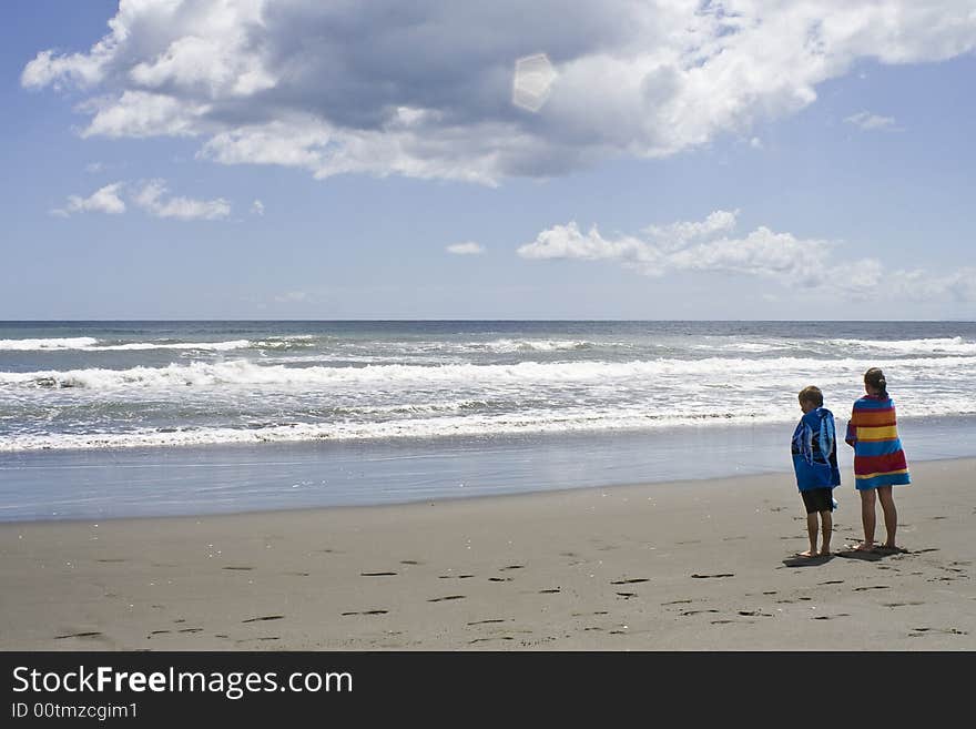 Children looking out to sea wrapped in towels after a swim