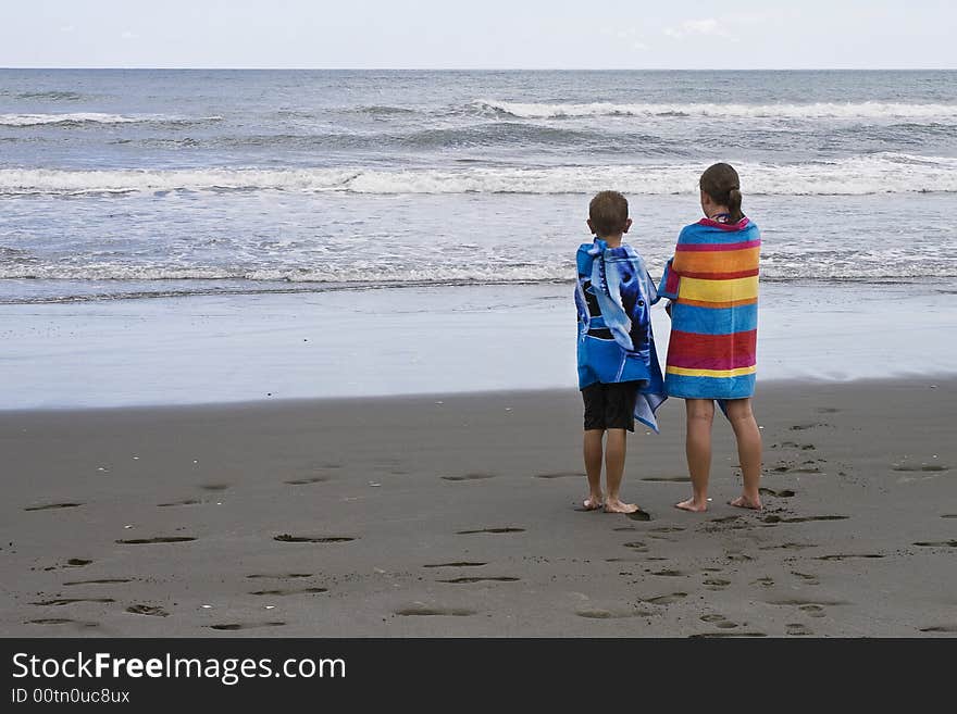 Children looking out to sea wrapped in towels after a swim