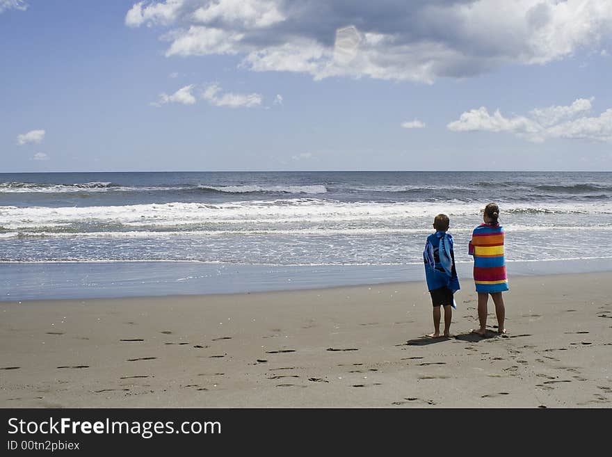 Children looking out to sea wrapped in towels after a swim