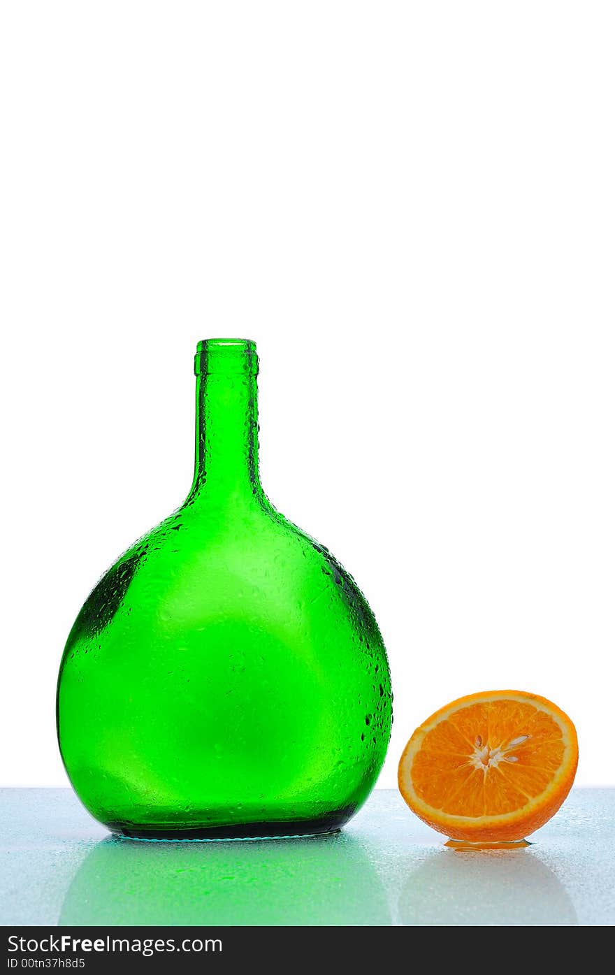 Green bottle with water drops and fresh orange. Green bottle with water drops and fresh orange