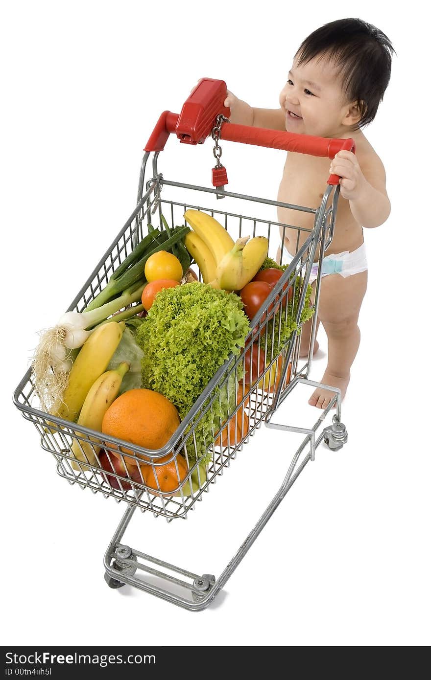 Baby pushes a shopping cart with fruits and vegetables before a white background. Baby pushes a shopping cart with fruits and vegetables before a white background