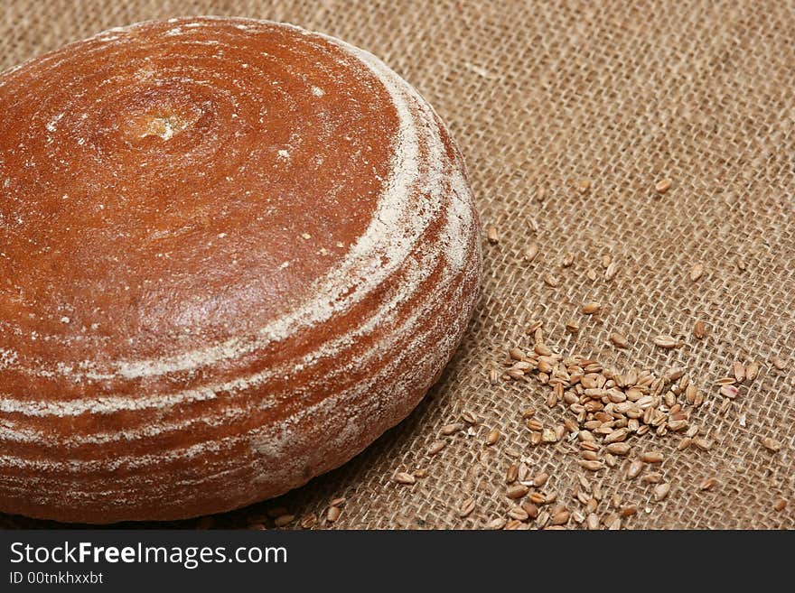 A closeup of a round loaf of bread with wheat grains. A closeup of a round loaf of bread with wheat grains.