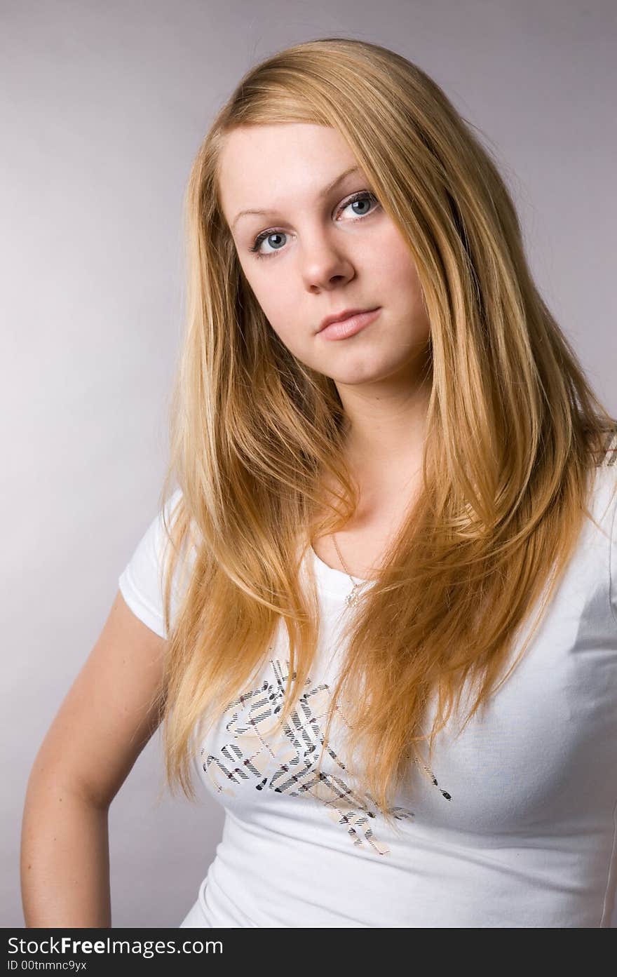 The smiling blonde on a grey background in studio.