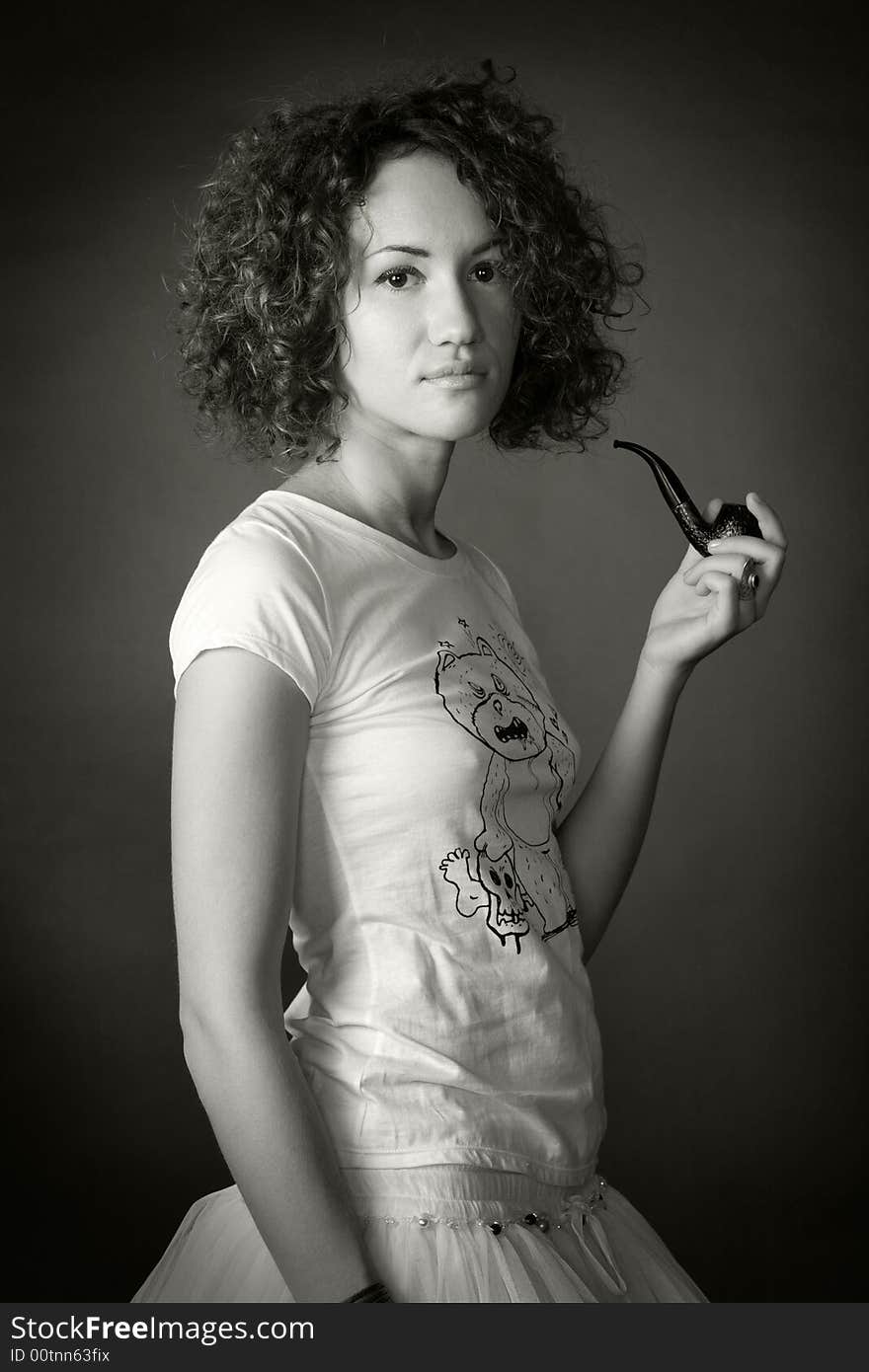 Portrait of a woman with curled hair smoking pipe in studio on a black background. Portrait of a woman with curled hair smoking pipe in studio on a black background