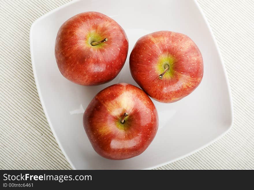 Three apples on white plate