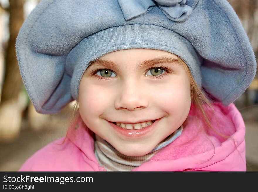 Happy smiling little girl wearing big blue hat in the street. Happy smiling little girl wearing big blue hat in the street