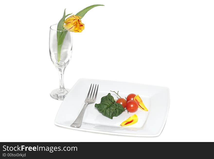 Still life of vegetables on a plete and flower in a glass. Still life of vegetables on a plete and flower in a glass