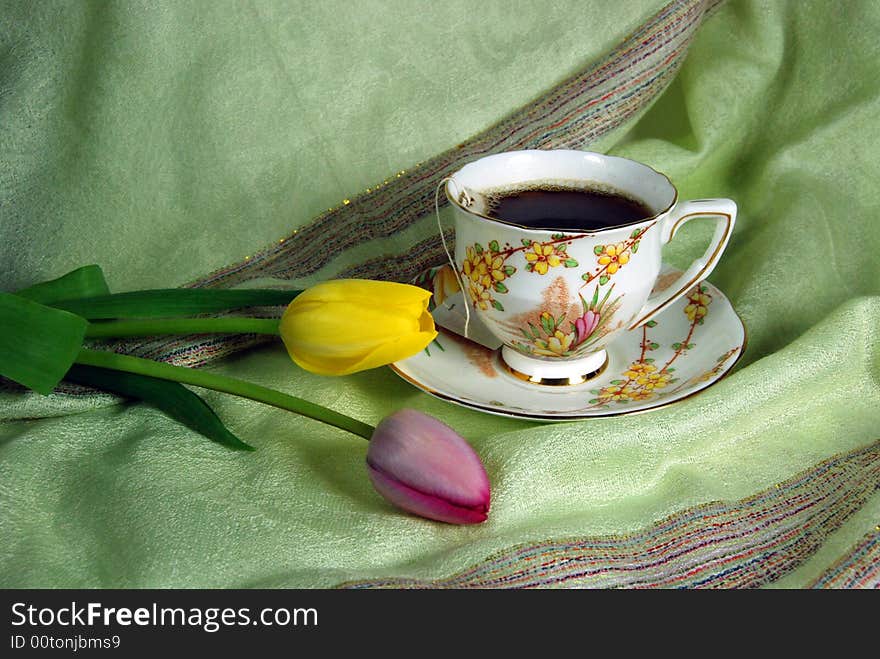 Antique tea cup and saucer with spring tulips on linen. Antique tea cup and saucer with spring tulips on linen.