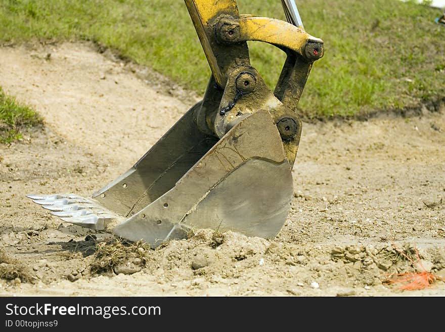 The shovel end of a backhoe is displayed with its shinning teeth