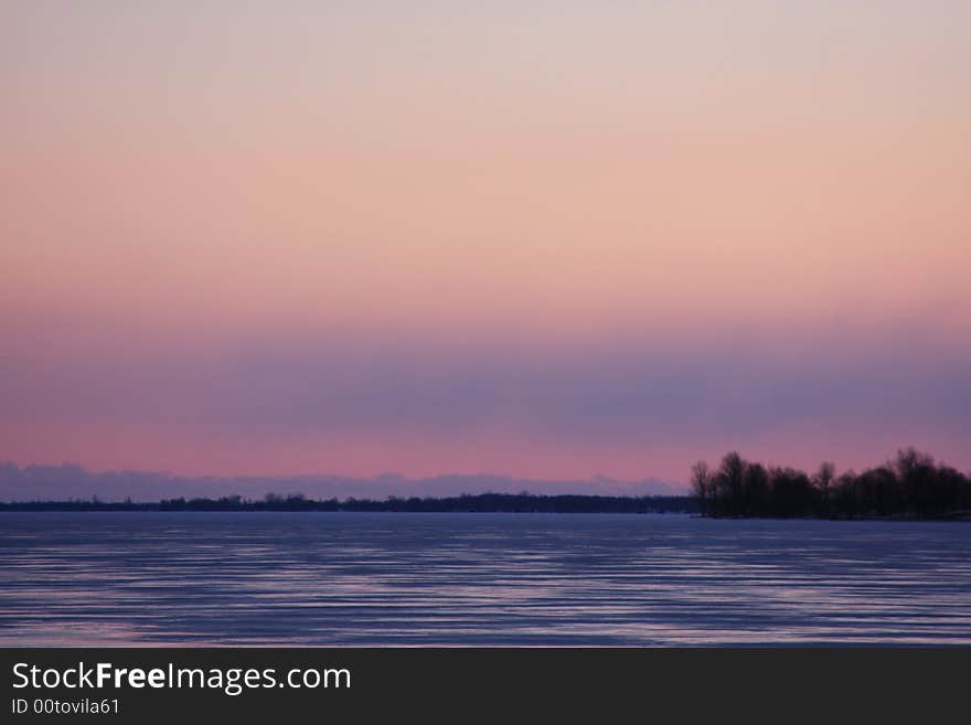 A frozen bay in northern New York is colored as the Sun sets nearby. A frozen bay in northern New York is colored as the Sun sets nearby.