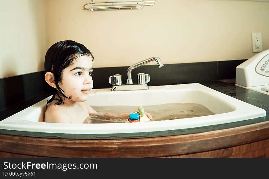 This child is having bath in a normal washbasin. This child is having bath in a normal washbasin.