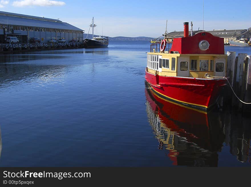 Old red boat in harbour with reflection