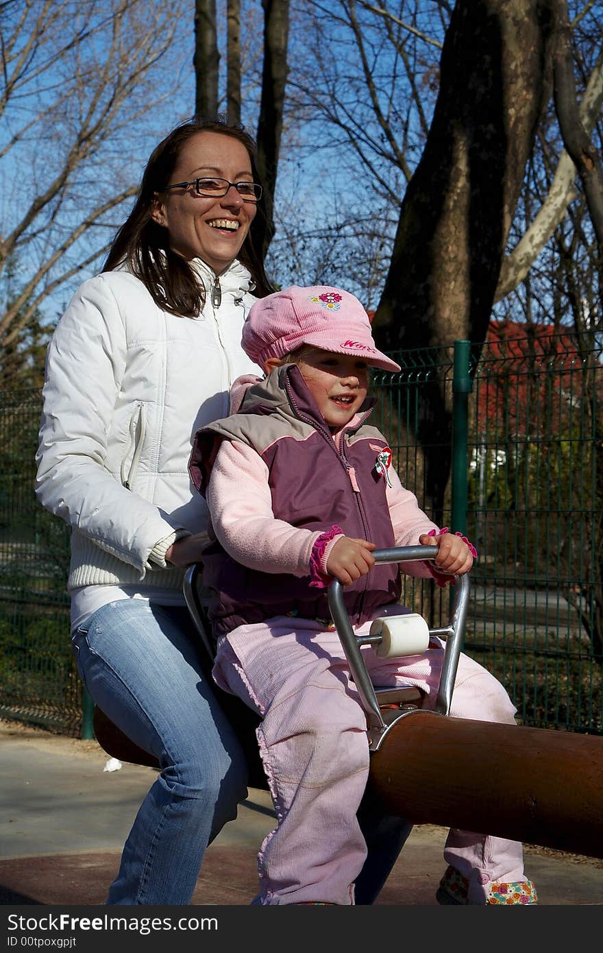 Young girl and children smiling in tandem seesaw.
