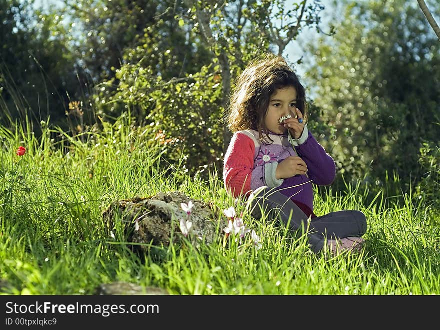 Girl sitting in grass smelling a flower