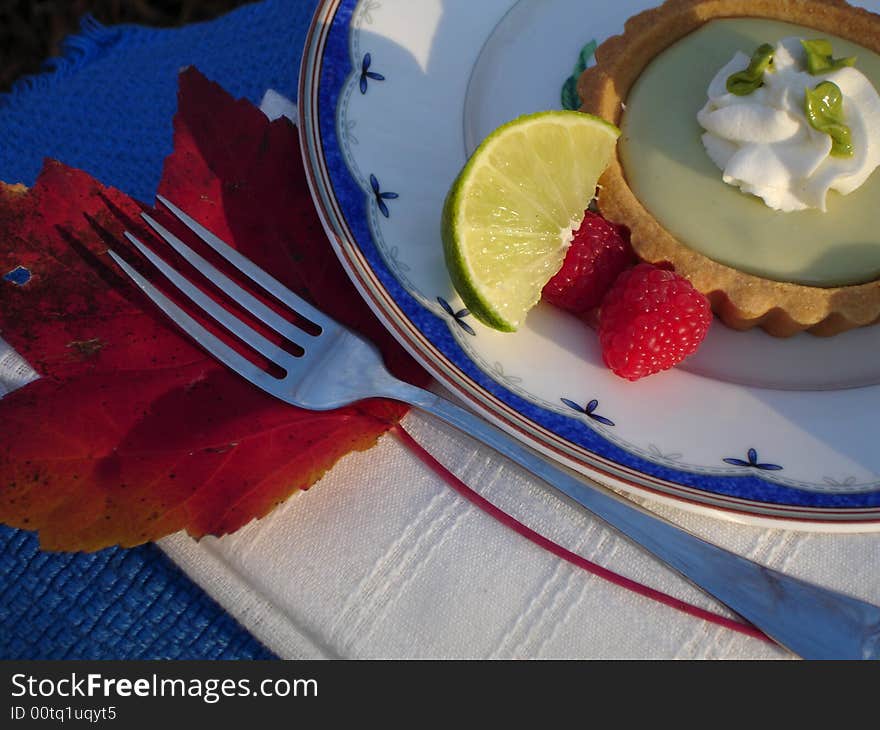 Key Lime tart with lime wedge and raspberries. Key Lime tart with lime wedge and raspberries