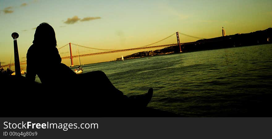 Silhouette of a woman sitting on the harbour at sunset. Silhouette of a woman sitting on the harbour at sunset