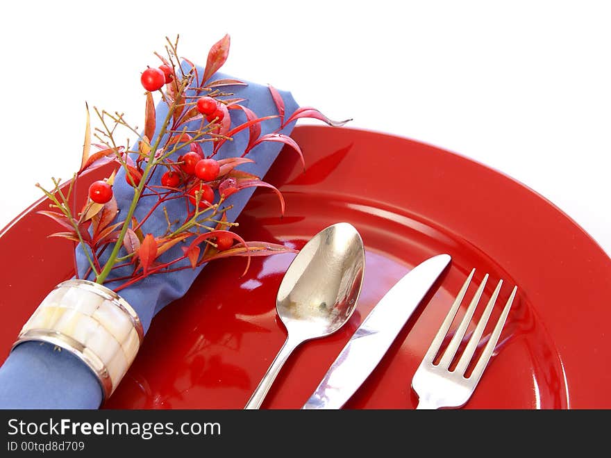 Elegant table setting in red and blue, with fresh sprigs of leaves and berries