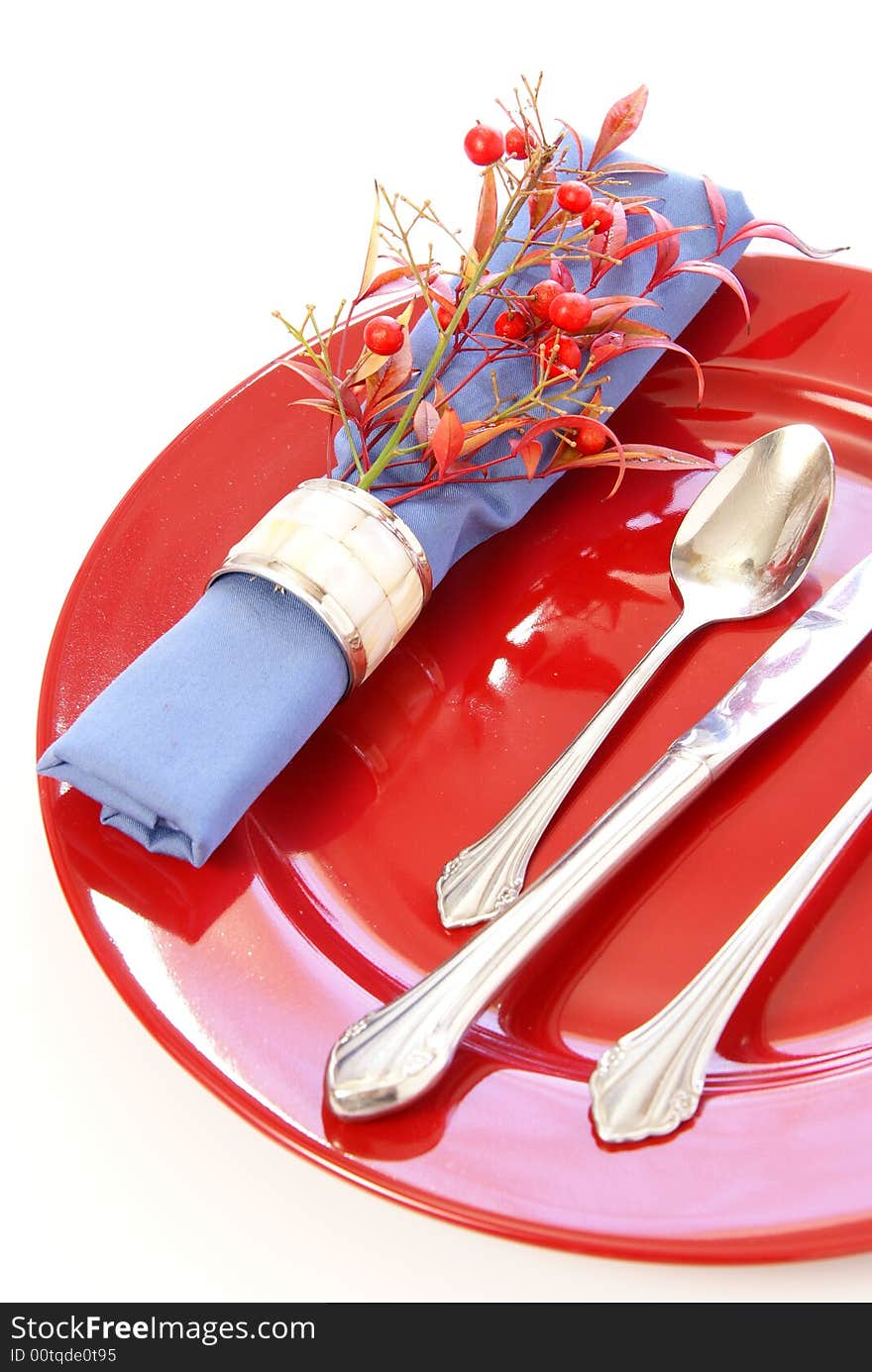 Elegant table setting in red and blue, with fresh sprigs of leaves and berries